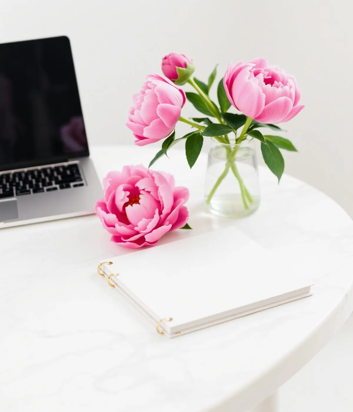 Elegant marketing workspace with peonies and a planning notebook